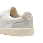 Close-up rear angle focusing on the Cool Light Gray suede heel counter, stamped metallic gold PUMA Cat emblem, soft cream collar lining, and the textured off-white rubber cupsole base.