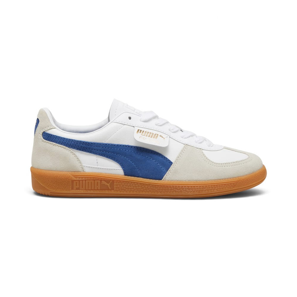 Lateral view showing the crisp Puma White smooth leather upper, Vapor Gray suede T-toe and heel overlays, vibrant Clyde Royal blue suede Formstrip, signature fold-over lateral flap tab stamped with gold foil PUMA branding, and textured gum rubber cupsole with debossed PUMA lettering. Main image