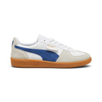 Lateral view showing the crisp Puma White smooth leather upper, Vapor Gray suede T-toe and heel overlays, vibrant Clyde Royal blue suede Formstrip, signature fold-over lateral flap tab stamped with gold foil PUMA branding, and textured gum rubber cupsole with debossed PUMA lettering.