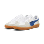 Forward three-quarter angle showcasing both shoes side by side, highlighting the low-profile terrace silhouette, flat white laces, contrasting suede T-toe mudguards, blue suede Formstrips, and clean gum rubber soles.