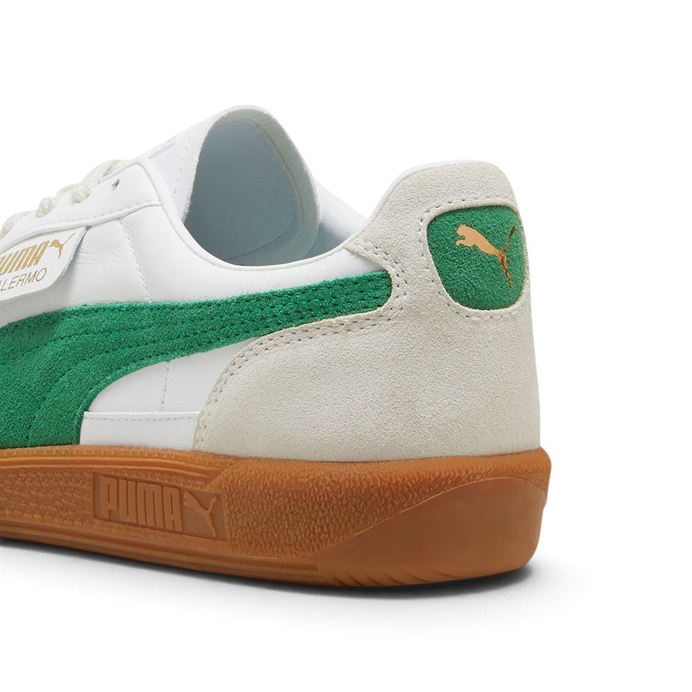 Close-up rear angle focusing on the Vapor Grey suede heel counter, Archive Green suede heel moustache tab stamped with a gilded metallic PUMA Cat logo, soft white collar lining, and textured gum cupsole base.