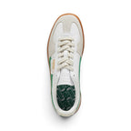 Direct overhead view of the shoe, displaying the Vapor Grey suede T-toe mudguard, white leather vamp, flat off-white laces, embossed white leather tongue, fold-over PUMA flap label, and green cushioned footbed printed with repeating PUMA logos.