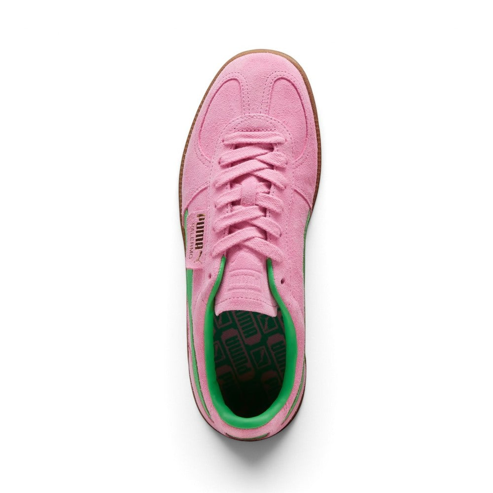 Direct overhead view of the shoe, displaying the suede T-toe overlay, flat tonal pink laces, embossed pink suede tongue, fold-over PUMA flap label, and vibrant green footbed patterned with repeating black PUMA branding.