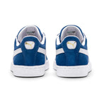Focuses on the rear profile of both shoes, displaying the Olympian Blue suede heel counters, White leather moustache tabs stamped with metallic gold PUMA Cat emblems, and debossed PUMA branding across the rear rubber heel bumper.