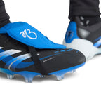 Close-up shot of a player's feet wearing the signature boots, focusing on the blue heel counter adorned with Jude Bellingham's iconic silhouette celebration graphic and the specialized firm ground studs.