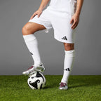 Player wearing the silver and burgundy Predator Elite boots while resting a foot atop a football on an artificial turf pitch.