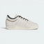 Highlights the high-velocity sweep of the tonal Talc leather 3-Stripes, showing the professional, matte texture of the cream panels and the sharp contrast carbon lining resting above the clean cream rubber midsole wall.