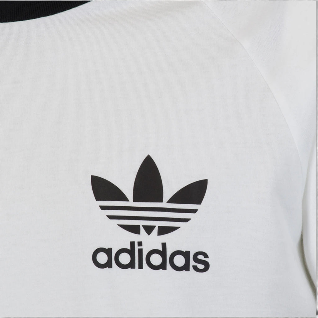 Zoom Looking at the Front Branding: Macro focus on the crisp black printed adidas Trefoil logo and wordmark against the fine-grained white cotton fabric texture.   