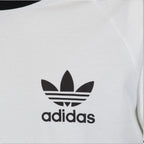 Zoom Looking at the Front Branding: Macro focus on the crisp black printed adidas Trefoil logo and wordmark against the fine-grained white cotton fabric texture.   
