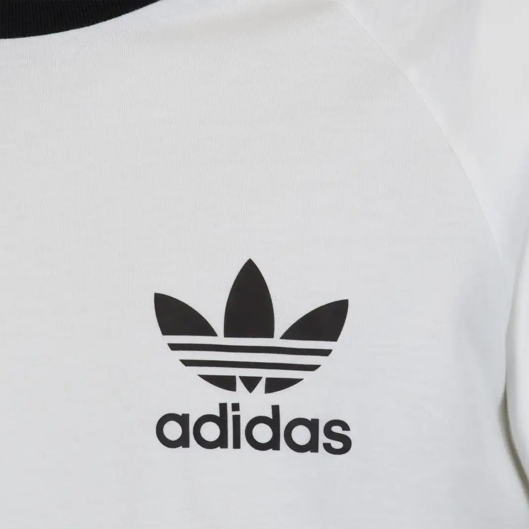 Close-up zoom on the fabric of the Adidas California T-Shirt, showing the soft cotton texture and the detailed black Trefoil logo and 3-Stripes print.