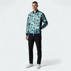 Man wearing a patterned jacket and black pants on a white background