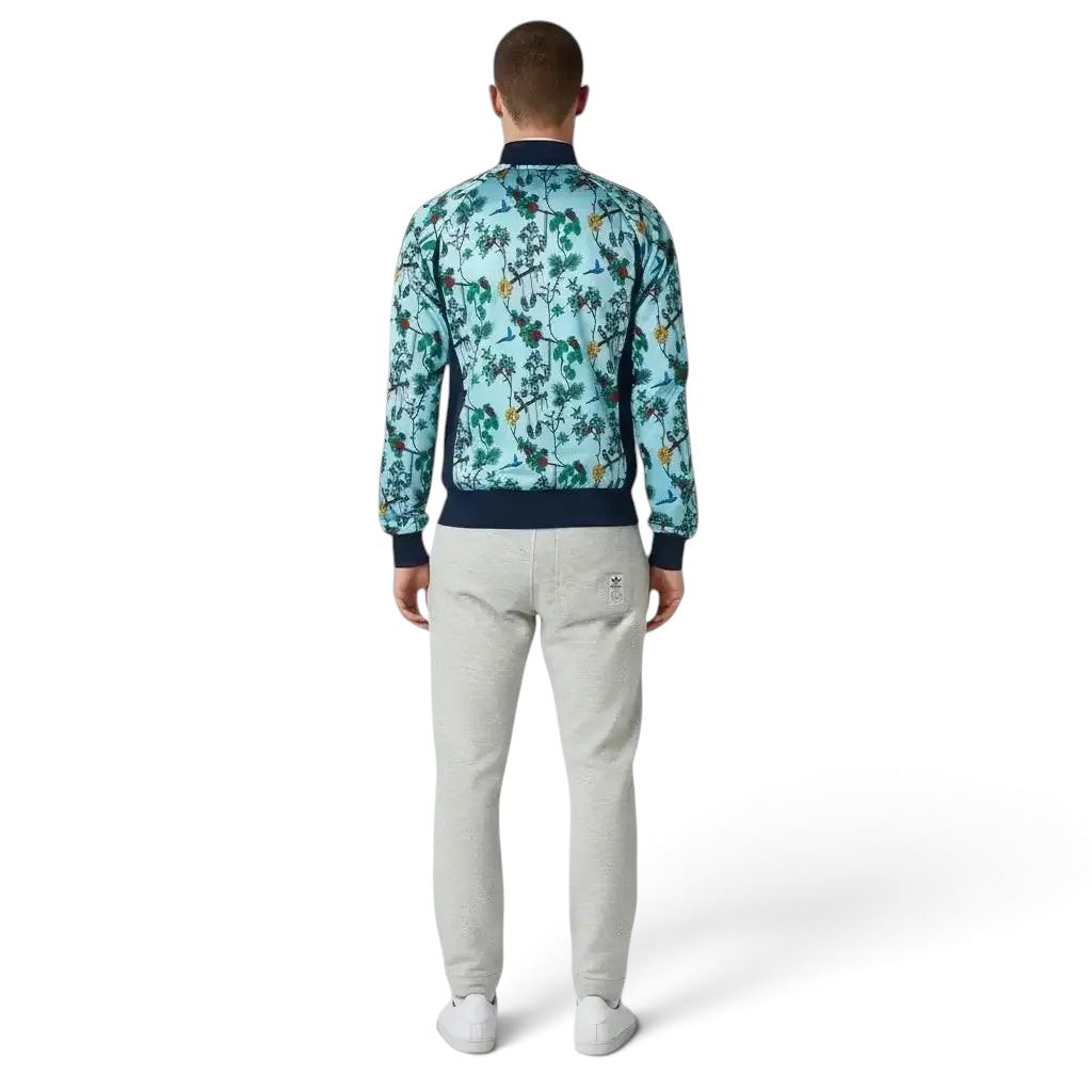 Man wearing a floral patterned jacket and light gray pants on a white background