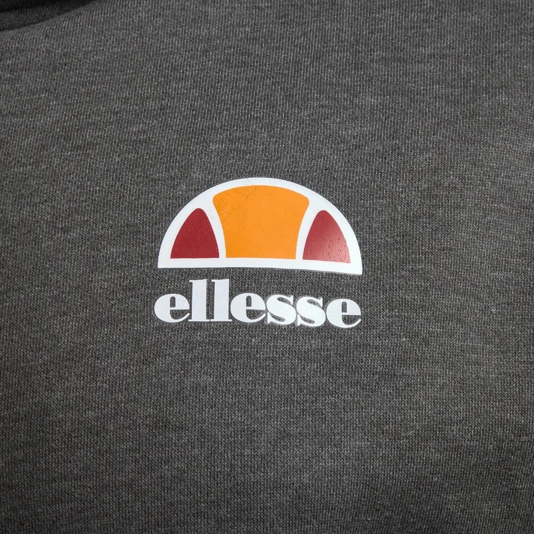 Close-up zoom on the fabric of the Ellesse Toce Overhead Hoodie in charcoal, showing the soft fleece texture and the embroidered or printed Ellesse logo.