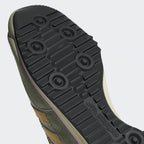 Close-up of a green shoe sole with brand logo on a light gray background