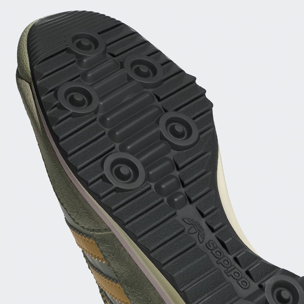 Close-up of a green shoe sole with brand logo on a light gray background