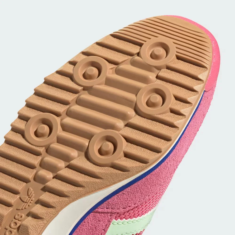 Close-up of a pink and green sneaker with a brown sole on a light gray background