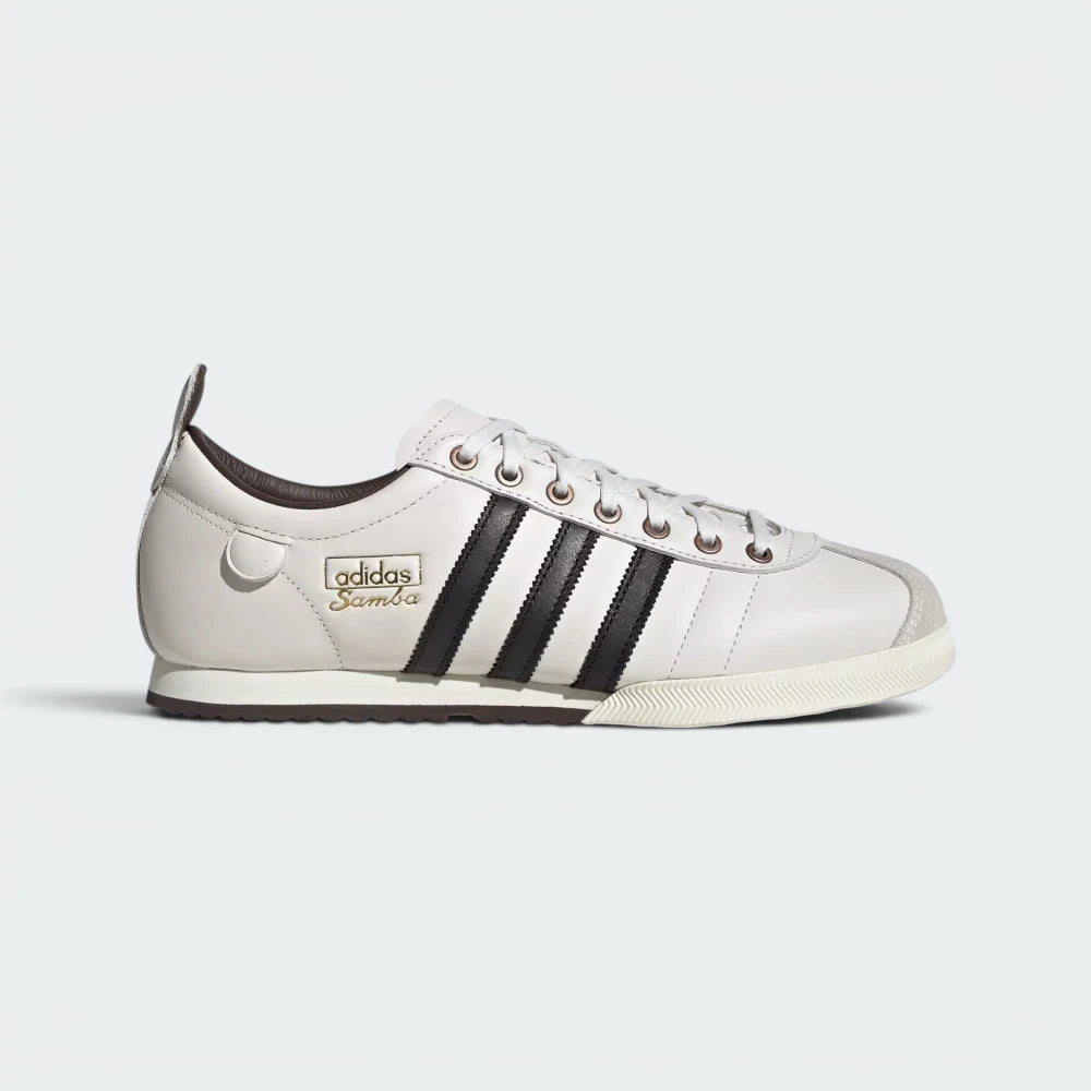 Highlights the high-velocity sweep of the Core Black serrated 3-Stripes and the professional, gleaming depth of the metallic gold foil Samba branding.