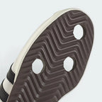 Close-up of a shoe sole with a textured pattern and three white hexagonal studs on a light gray background.