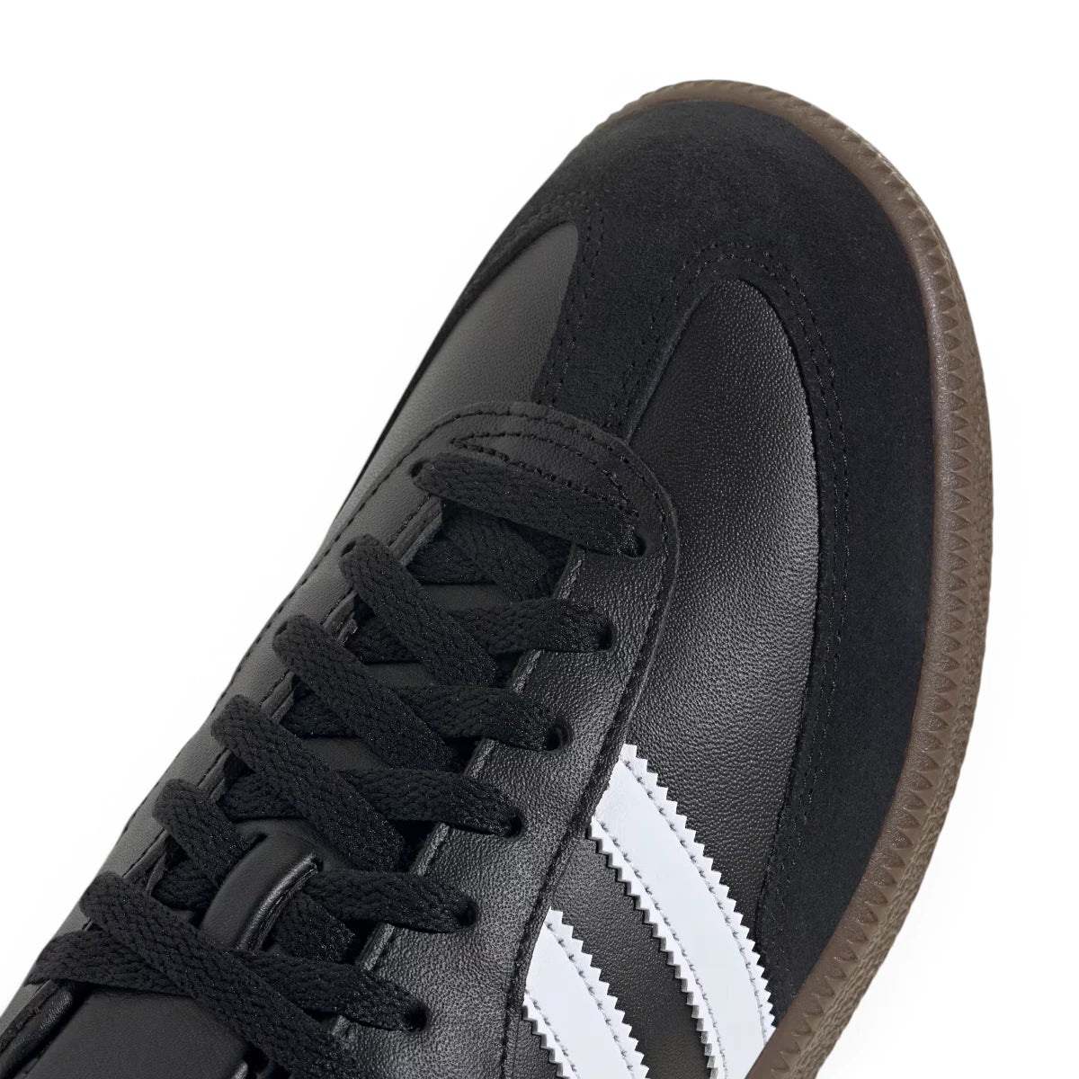 Macro focus on the durable black suede T-toe overlay, perforated toe box detailing, and crisp white serrated three stripes.