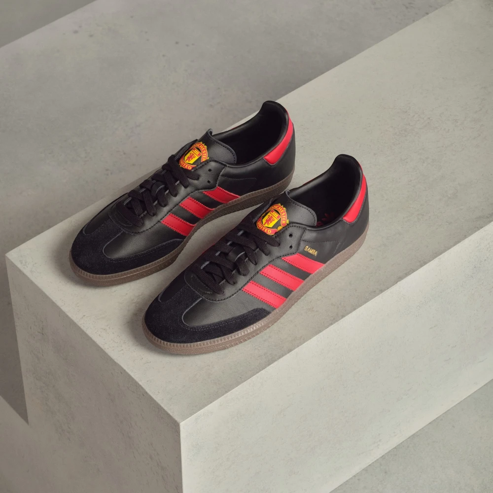 Looking down at the black lacing system and the official Manchester United badge on the tongue.
