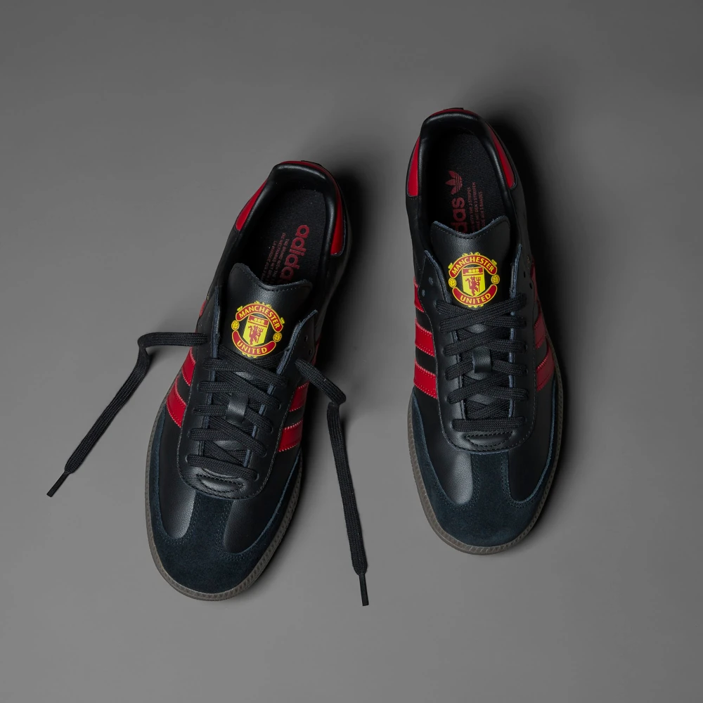 Looking down at the black lacing system and the official Manchester United badge on the tongue.