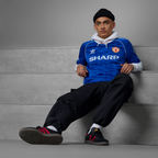 Person wearing a blue sports jersey with visible branding sitting on a gray wall.