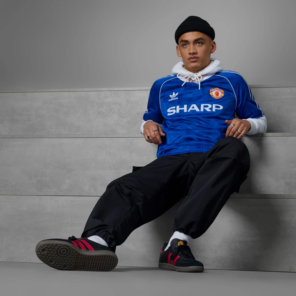 Person wearing a blue sports jersey with visible branding sitting on a gray wall.