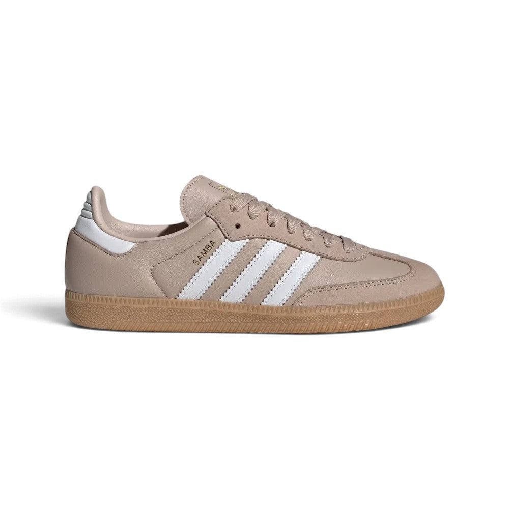 Displays the full lateral silhouette featuring the smooth Wonder Taupe leather upper, contrasting Cloud White serrated 3-Stripes, gleaming metallic gold foil "Samba" lettering, matching white heel tab, and the classic gum rubber cupsole.
