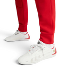 White sneakers with red accents worn with red pants on a light gray background
