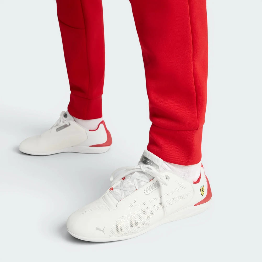 White sneakers with red accents worn with red pants on a light gray background