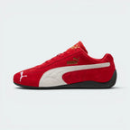 Highlights the high-velocity, low-slung silhouette of the shoe, showing the clean sweep of the white suede Formstrip against the vibrant red upper and the thin, textured black sole wrapping up the heel.