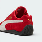 Focuses on the rounded driver's heel design, showcasing the tire-tread textured black rubber wrapping up the rear spine, finished with a small metallic gold Puma Cat logo.