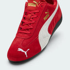 Highlights the "unreal" low-profile interface where the slim black rubber sole meets the red suede upper, emphasizing the minimalist motorsport design.
