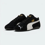Emphasises the low-profile, forward-leaning athletic stance of the trainers, highlighting the classic sport harmony of the black suede and white leather accents.