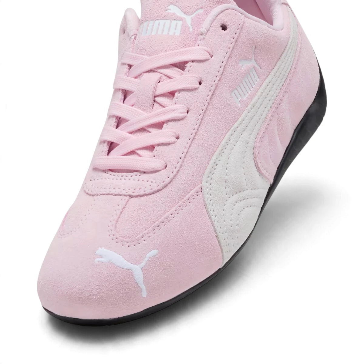 Macro focus on the front forefoot, detailing the fine pink suede texture, stitched central seam, and the embroidered white PUMA leaping cat on the toe.