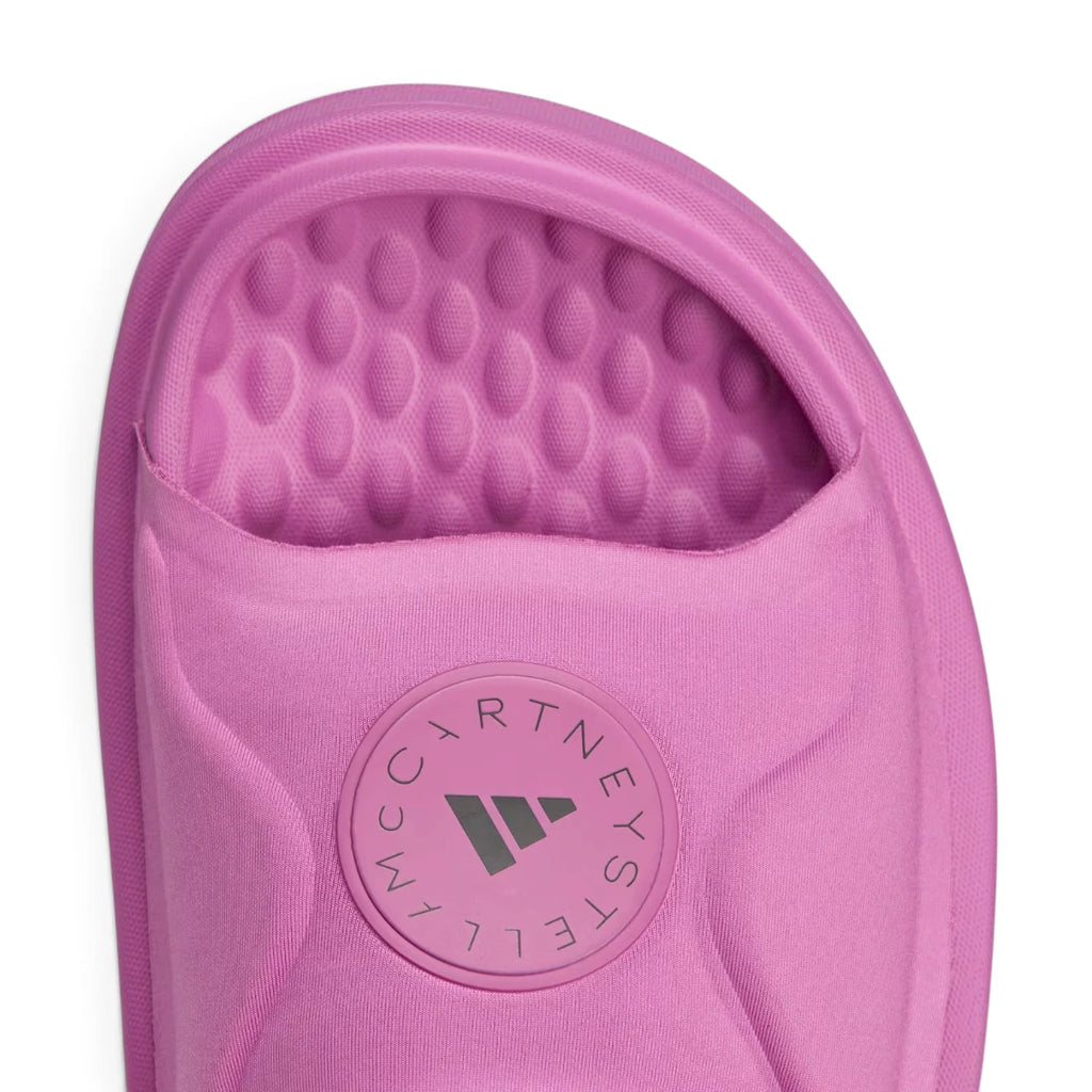 Close-up macro focus on the circular embossed badge featuring the Stella McCartney lettering and three-stripe graphic.