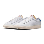 Three-quarter forward angle showcasing both sneakers side by side, highlighting their low-profile tennis silhouette, cream vulcanised midsoles, and blue heel accents.