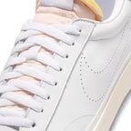 Macro focus on the forefoot and eyestay, detailing the fine leather grain, flat white laces, and perforated side Swoosh lines.   