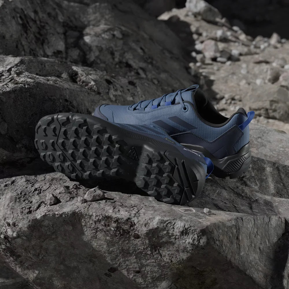 Blue athletic shoes with black soles on a rocky surface