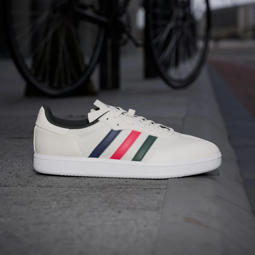 White sneaker with colorful stripes on a concrete surface with a blurred bicycle in the background