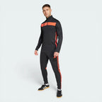 Man wearing a black and red tracksuit with Adidas logo on a white background