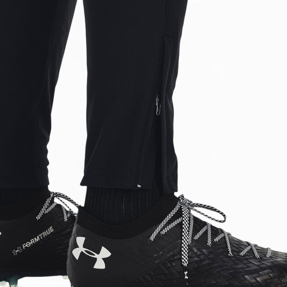 Details the lower leg construction, displaying the open black vertical ankle zip, ribbed cuff seam, and easy transition over black laced football boots.
