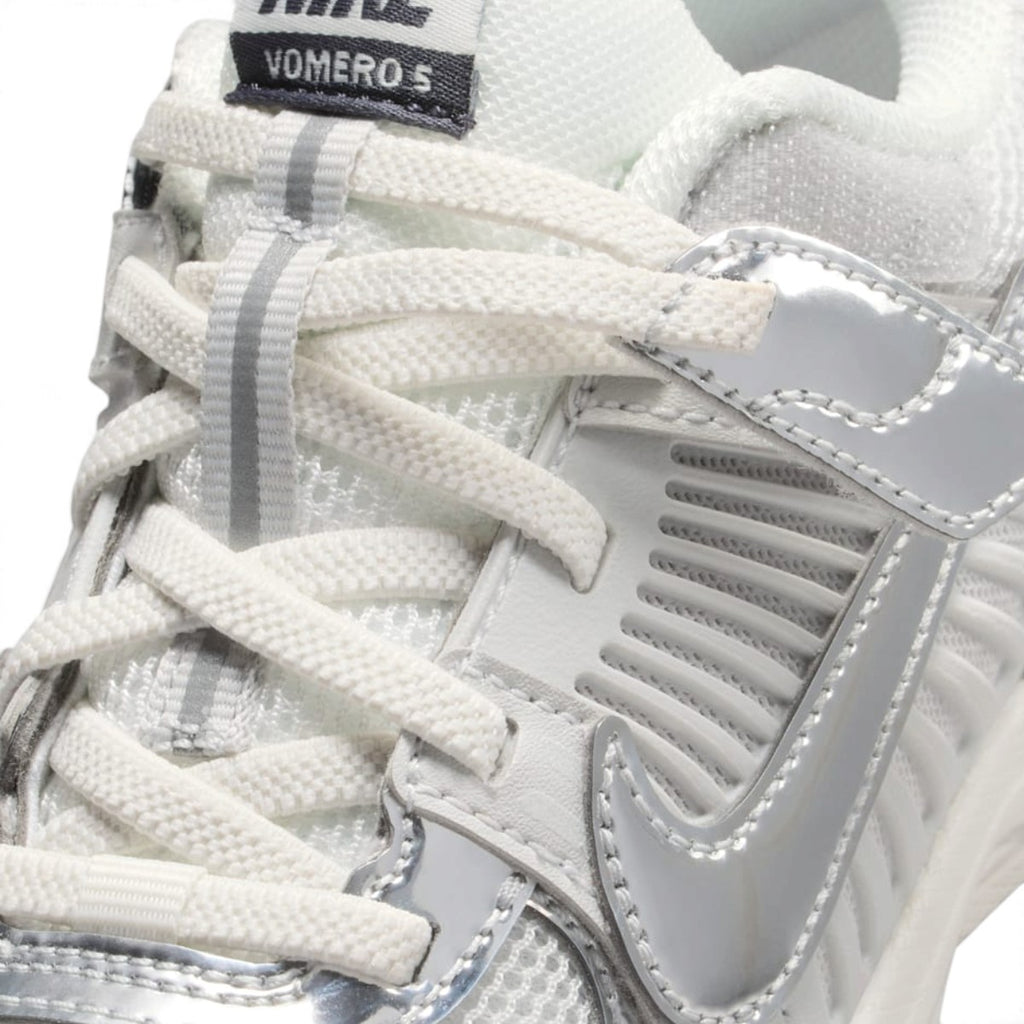 Macro close-up angle capturing the textured elastic laces, tongue badge, and side ventilation caging.