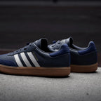 Focuses on the contoured shape of the dark leather heel tab and the reflective visibility patches embedded into the rear casing.