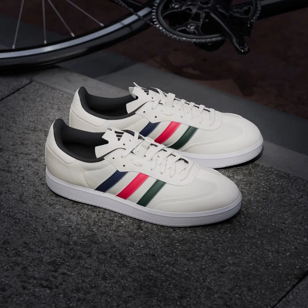 White sneakers with colorful stripes on a dark surface with a bicycle wheel in the background