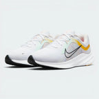 Emphasising the low-cut, athletic running stance and the professional harmony of the university gold and pale pink contrast panels against the neutral white background.