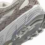 Sculpted Athletic Foam Midsole Texture, Gleaming Metallic Silver Swoosh Flank, Snakeskin-Embossed Leather Ribbing, and High-Traction Rubber Outsole Lugs, demonstrating the shock-absorbing foam depth and track-tested tooling.