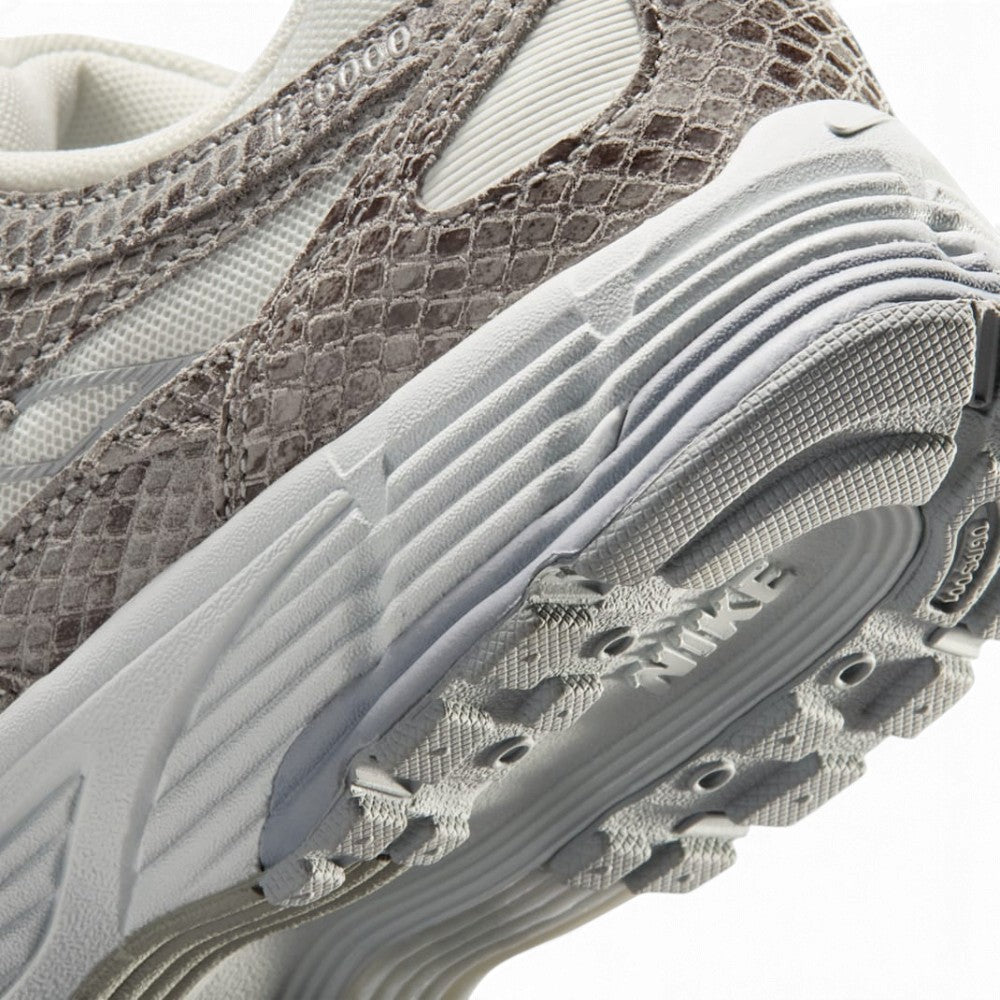 Sculpted Athletic Foam Midsole Texture, Gleaming Metallic Silver Swoosh Flank, Snakeskin-Embossed Leather Ribbing, and High-Traction Rubber Outsole Lugs, demonstrating the shock-absorbing foam depth and track-tested tooling.