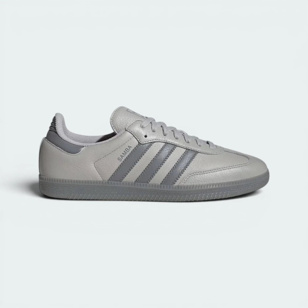Side profile of the Grey Two Adidas Samba OG, showcasing the tonal grey leather upper and the iconic serrated Three Stripes. Main image