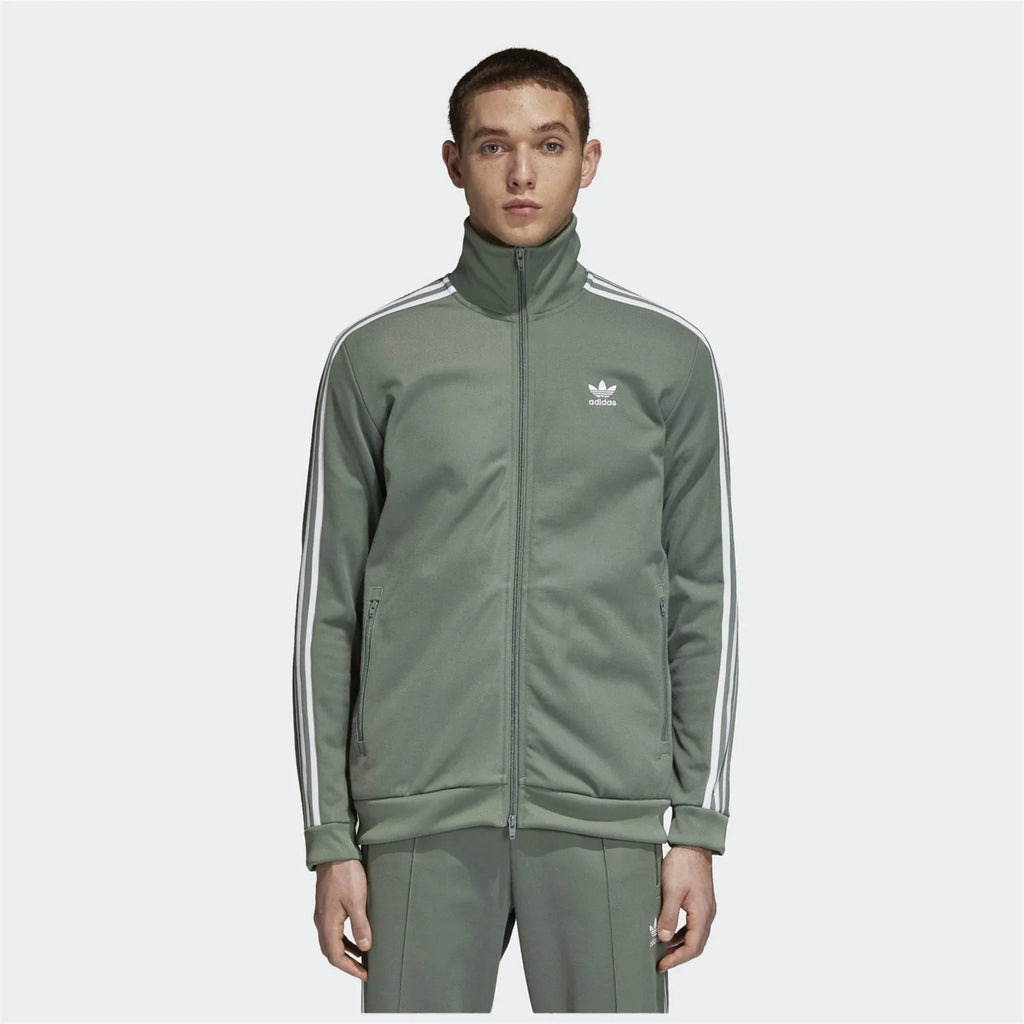 Person wearing a green Adidas tracksuit on a white background